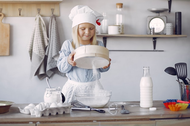 Menina de chapéu branco shef cozinhar a massa para biscoitos Foto gratuita