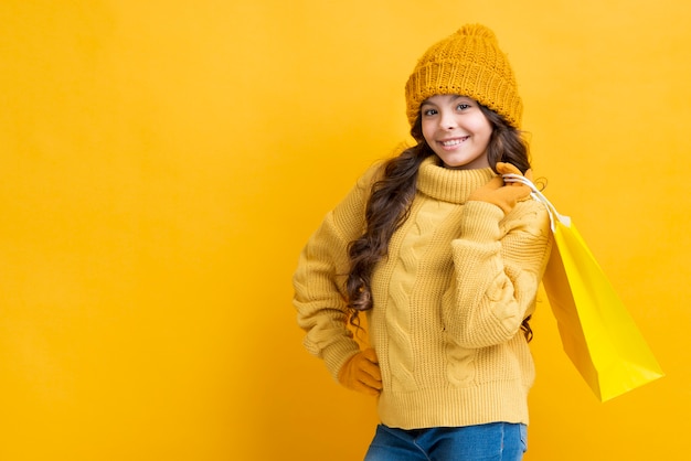 Menina de cópia-espaço com saco de roupas de compras de inverno Foto gratuita