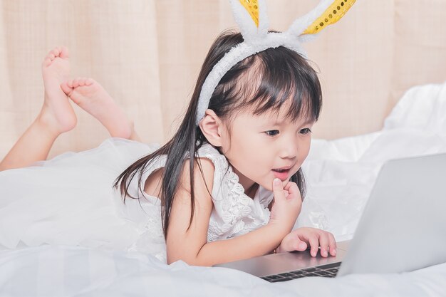 Menininha, mentindo, com, laptop, cama, feliz, sorrindo, pensando, com, tecnologia, conceito Foto Premium
