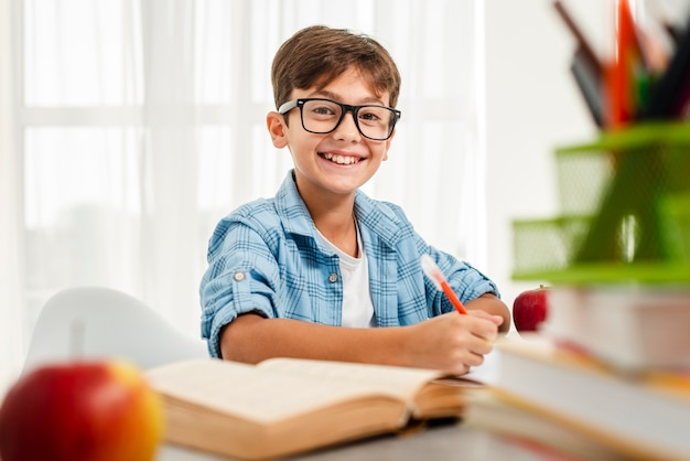 Menino sorridente de alto ângulo com óculos estudando Foto gratuita