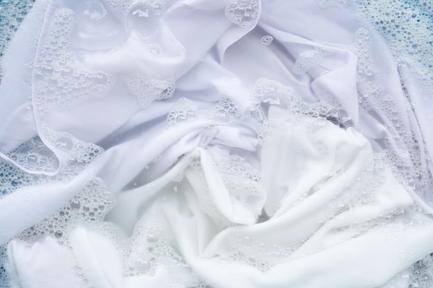 Mergulhe as roupas brancas na dissolução da água com detergente em pó Foto Premium