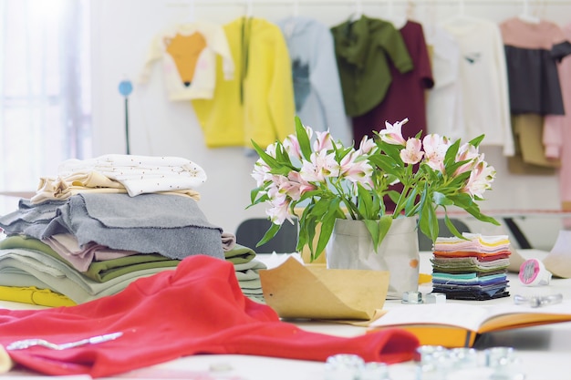 Mesa de designer de moda criativa ou local de trabalho com equipamentos de costura, tecidos, modelos, escritório de inspiração estilista moderna, atelier de costureira com roupas Foto Premium