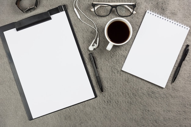Mesa de escritório cinza com xícara de café; fone de ouvido e óculos Foto gratuita