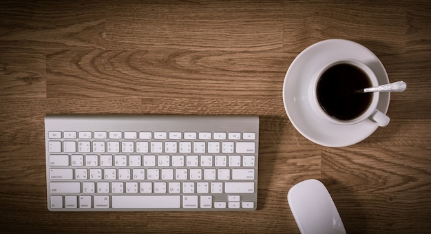 Mesa de escritório com computador de teclado e xícara de café e mouse de computador Foto Premium