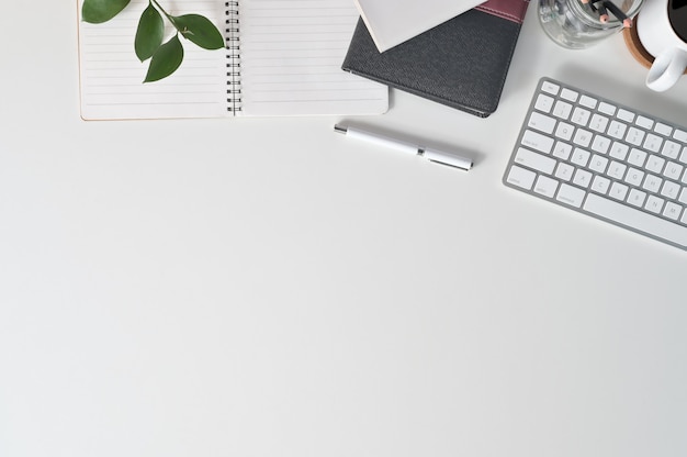Mesa de escritório com computador do teclado do espaço da cópia da vista superior, café, papel do caderno e material de escritório na mesa de escritório. Foto Premium