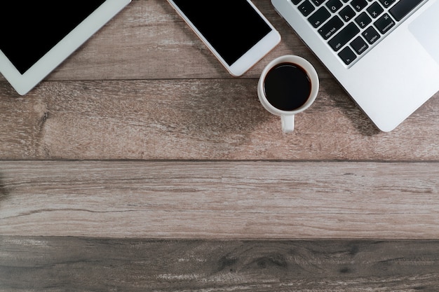 Mesa de escritório de madeira com computador, tablet e telefone inteligente com xícara de café Foto Premium