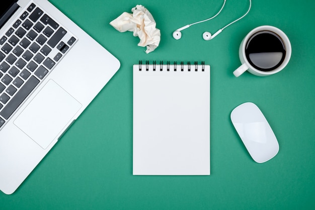 Mesa de mesa de escritório de design moderno com página de caderno em branco, computador portátil e café Foto Premium