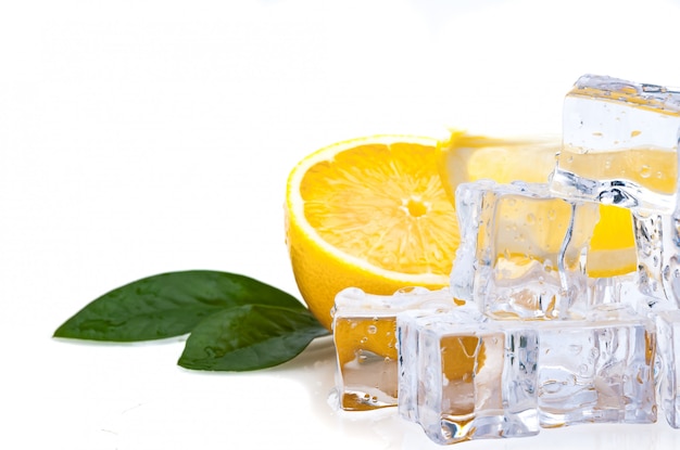 Metade de um limão fresco, brilhante, com folhas verdes e cubos de gelo frio Foto Premium