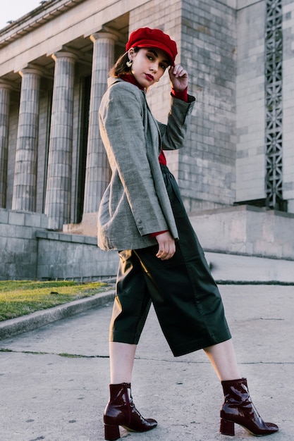 Moda jovem mulher com a mão no seu boné vermelho, olhando para a câmera Foto gratuita