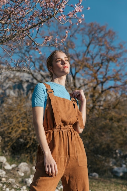 Modelo feminino posando sob a árvore de florescência Foto gratuita
