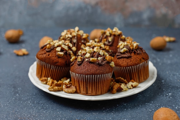 Muffins de chocolate e nozes com uma xícara de café com nozes na superfície escura Foto gratuita