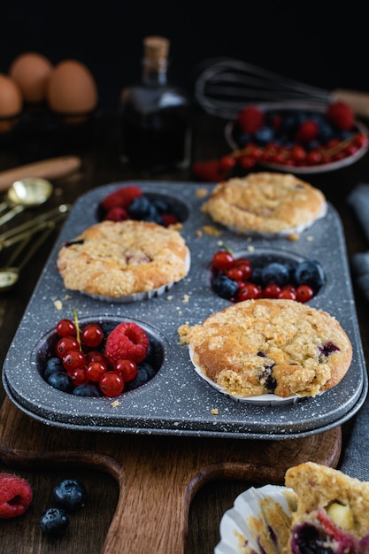 Muffins de streusel com mirtilo, framboesa e groselha na mesa de madeira rústica Foto Premium