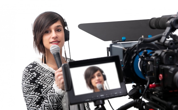 Muito jovem jornalista apresentando relatório no estúdio de televisão em branco Foto Premium