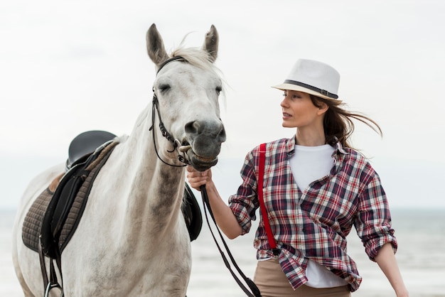 Mulher andando com um cavalo na praia Foto gratuita