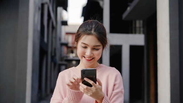 Mulher asiática alegre do blogger do mochileiro que usa o smartphone para o sentido e olhando no mapa de lugar ao viajar no bairro chinês no pequim, china. conceito do feriado do curso de turista da trouxa do estilo de vida. Foto gratuita