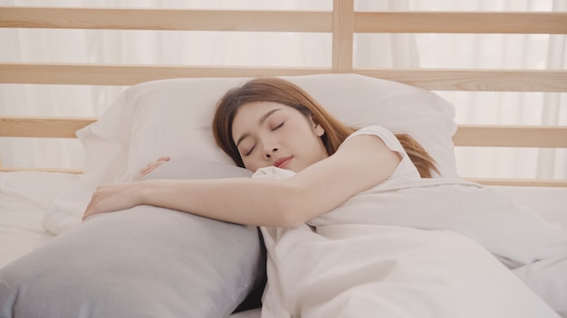 Mulher asiática sonhando enquanto dorme na cama no quarto Foto gratuita