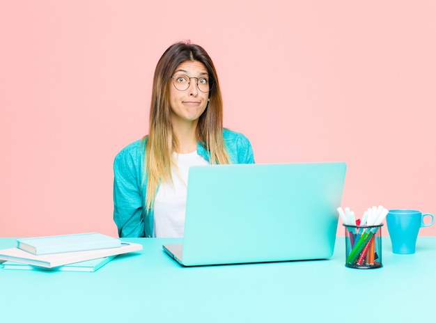 Mulher bonita e jovem trabalhando com um laptop se sentindo triste e estressada, chateada por causa de uma surpresa ruim, com um olhar negativo e ansioso Foto Premium