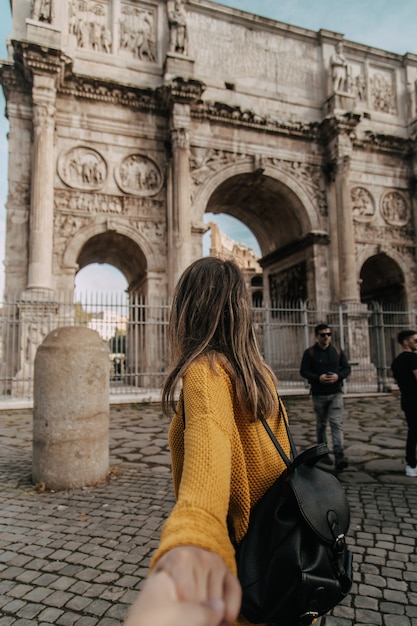 Mulher caminhando em direção ao arco de adriano com camisa amarela Foto Premium