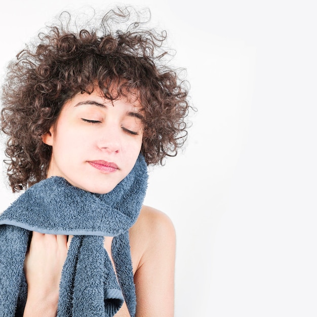 Mulher com cabelo encaracolado, limpando o rosto com toalha isolada no fundo branco Foto gratuita