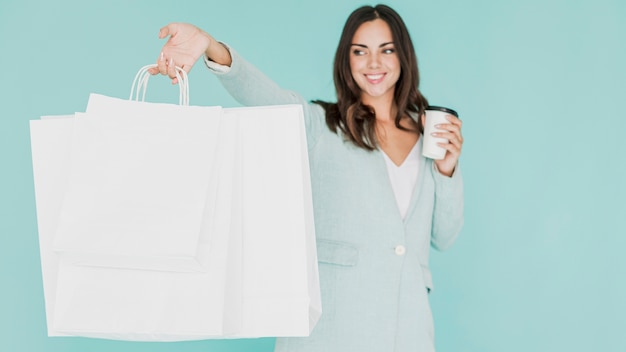 Mulher com café e sacolas em um fundo azul Foto gratuita
