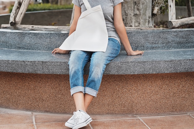 Mulher com saco de algodão branco em branco no parque Foto Premium