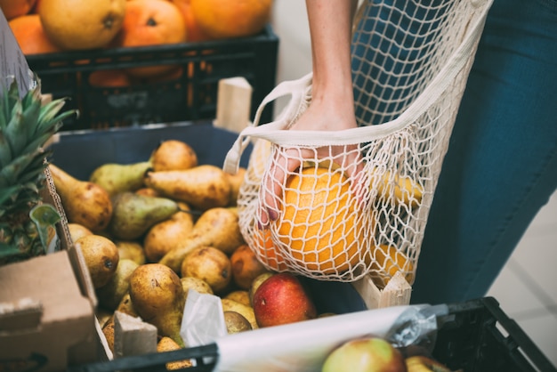 Mulher com saco de malha cheia de legumes frescos, compras na loja, conceito zero de resíduos Foto Premium