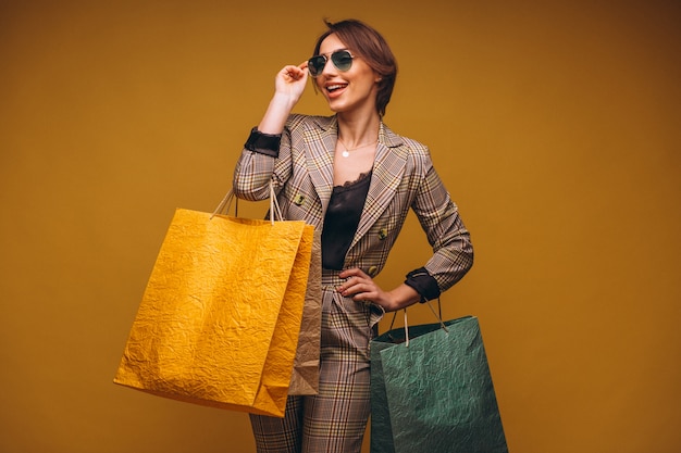 Mulher com sacos de compras no estúdio em fundo amarelo isolado Foto gratuita