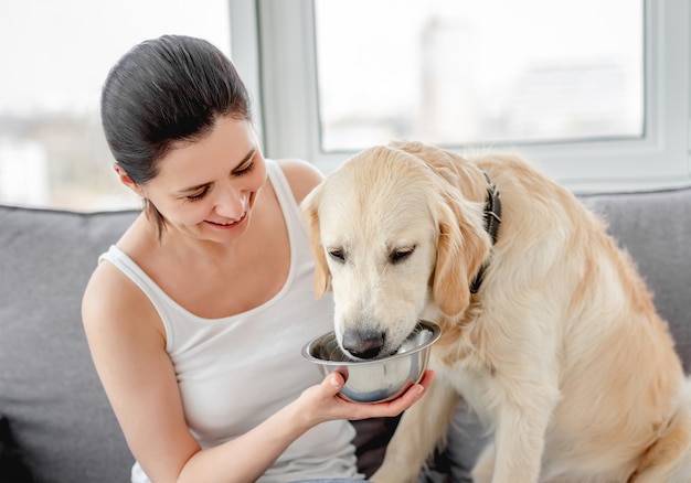 Mulher dando água para cachorro fofo | Foto Premium