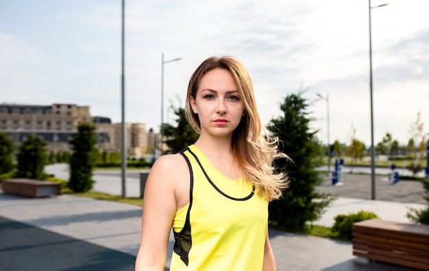 Mulher de esporte em roupas amarelas em um parque. Foto gratuita