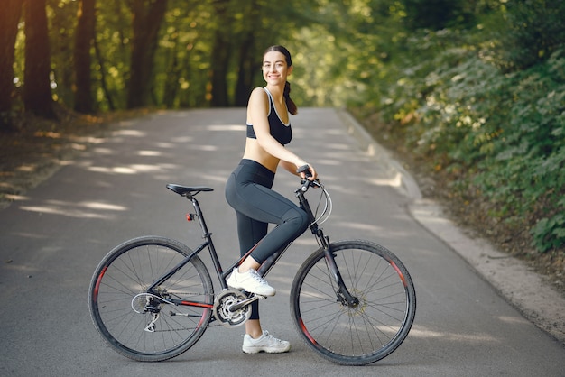 Mulher de esportes andando de bicicleta na floresta de verão Foto Grátis