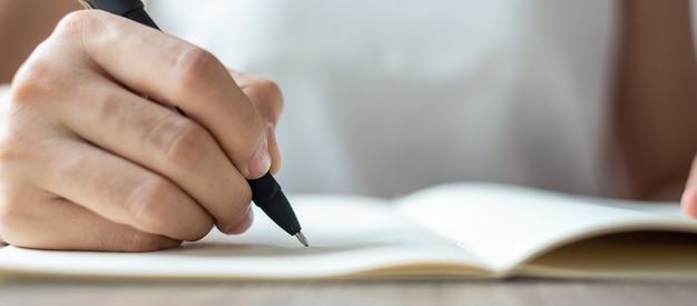 Mulher de negócios que escreve no caderno no escritório, mão da pena de terra arrendada da mulher com assinatura no relatório de papel. conceitos de negócios Foto Premium
