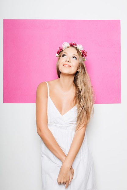 Mulher de vestido branco de algodão com flores no cabelo sorrindo Foto gratuita