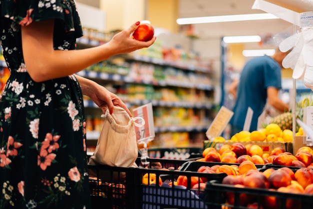 Mulher é escolhe mercado de alimentos de frutas e legumes. compras de sacolas reutilizáveis. desperdício zero Foto Premium