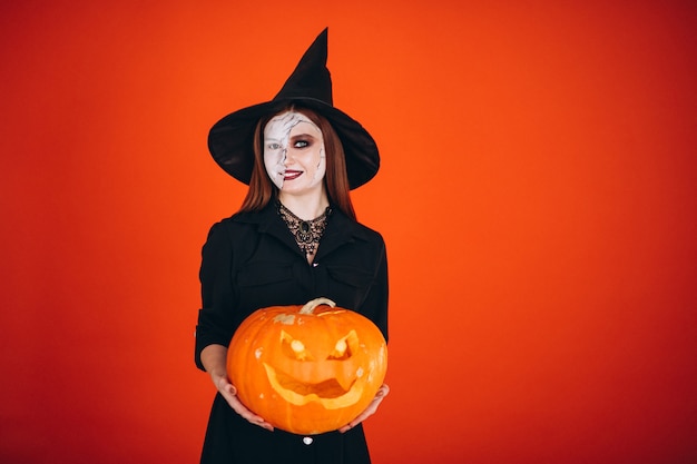 Mulher em uma fantasia de halloween com uma abóbora Foto gratuita