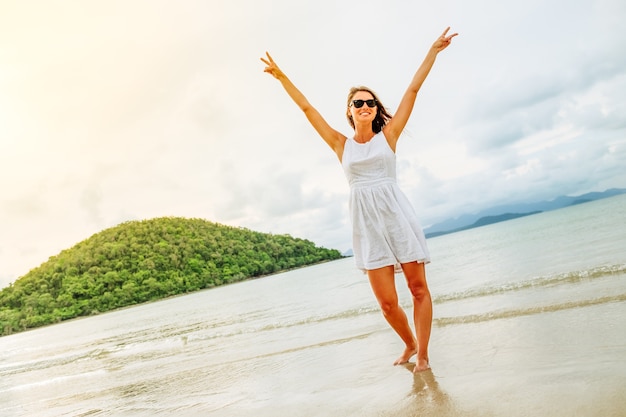 Mulher feliz com liberdade e braços erguidos na praia em dia de sol Foto Premium