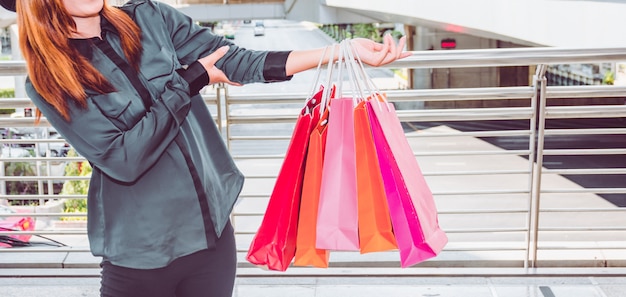 Mulher feliz com sacos de compras, aproveitando as compras. mulheres que compram, conceito do estilo de vida Foto Premium