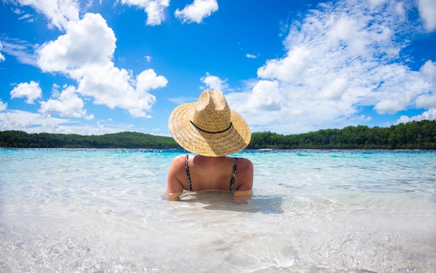 Mulher feliz desfrutando praia relaxar alegre no verão pela água azul tropical. Foto Premium