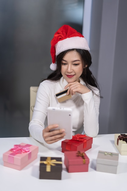 Mulher feliz no chapéu de papai noel, compras on-line para presente de natal com tablet Foto Premium