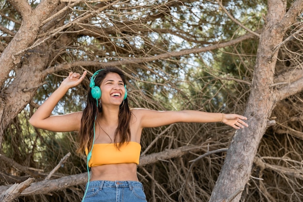 Mulher feliz no fone de ouvido ouvindo música na floresta Foto gratuita