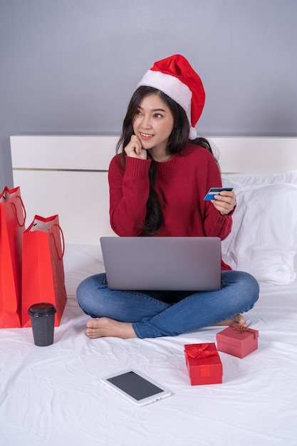 Mulher feliz pensando em compras on-line para presente de natal com laptop e cartão de crédito Foto Premium