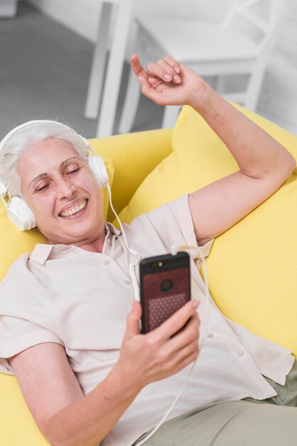 Mulher idosa feliz ouvindo música no fone de ouvido através do ...