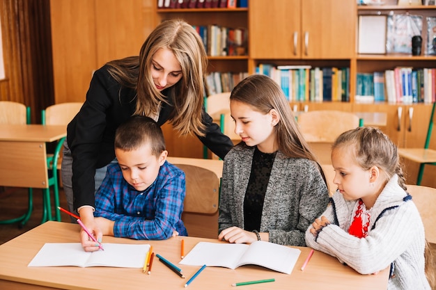 Mulher jovem, ajudando, estudantes, com, tarefa Foto gratuita