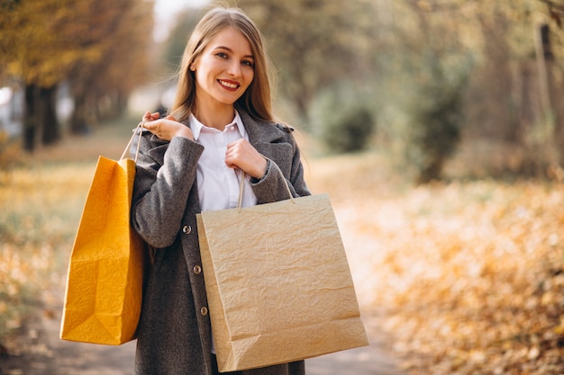Mulher jovem, com, bolsas para compras, andar, parque Foto gratuita