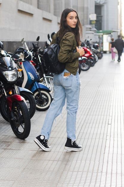 Mulher jovem, com, dela, mochila, andar, ligado, calçada Foto gratuita