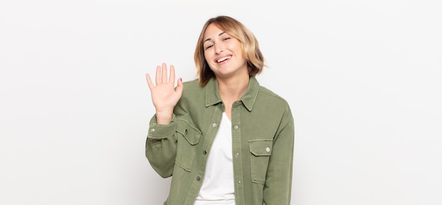 mulher jovem e bonita sorrindo feliz e animada acenando com a mão