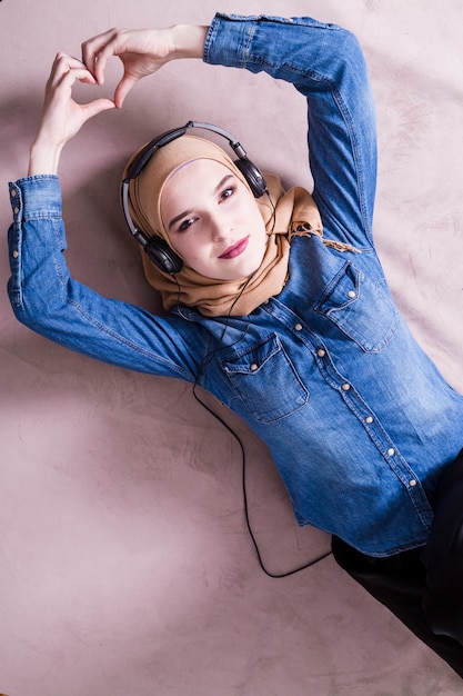 Mulher muçulmana ouvindo música em fones de ouvido Foto gratuita