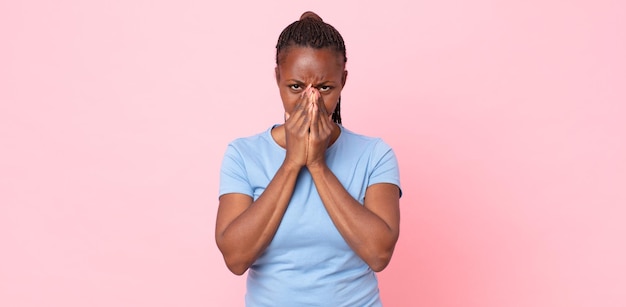 Mulher negra negra adulta preocupada esperançosa e religiosa orando fielmente com as palmas