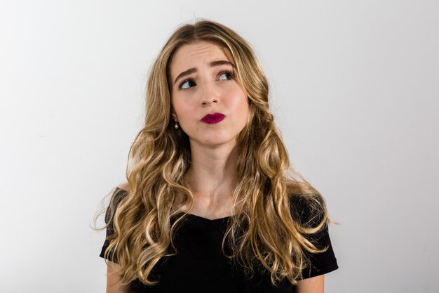 Mulher pensativa no fundo branco. olhando para cima com espaço para texto Foto Premium