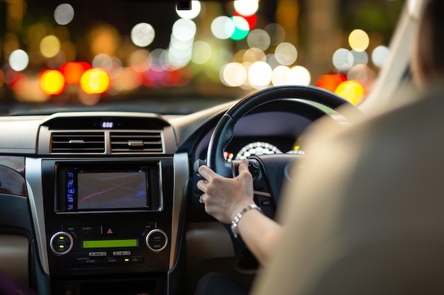 Mulher que conduz um carro com luzes do bokeh do engarrafamento no nighttime. Foto Premium