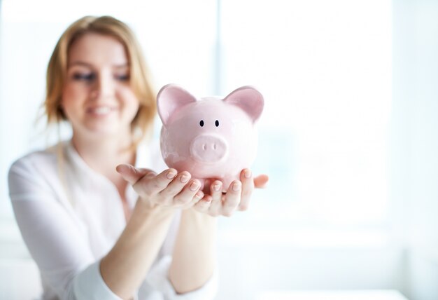 Mulher que prende um banco piggy Foto gratuita
